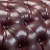 Oxblood red leather armchair featuring tufted design and solid wood frame”