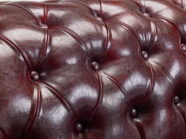 Oxblood red leather armchair featuring tufted design and solid wood frame”
